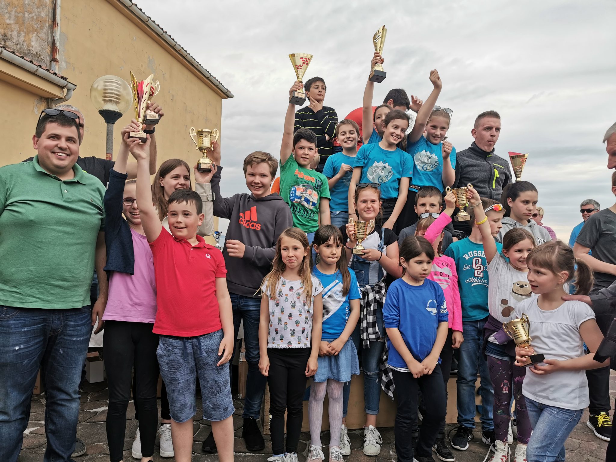 Skupina mlajših, ki razkazujejo priznanja in nagrade