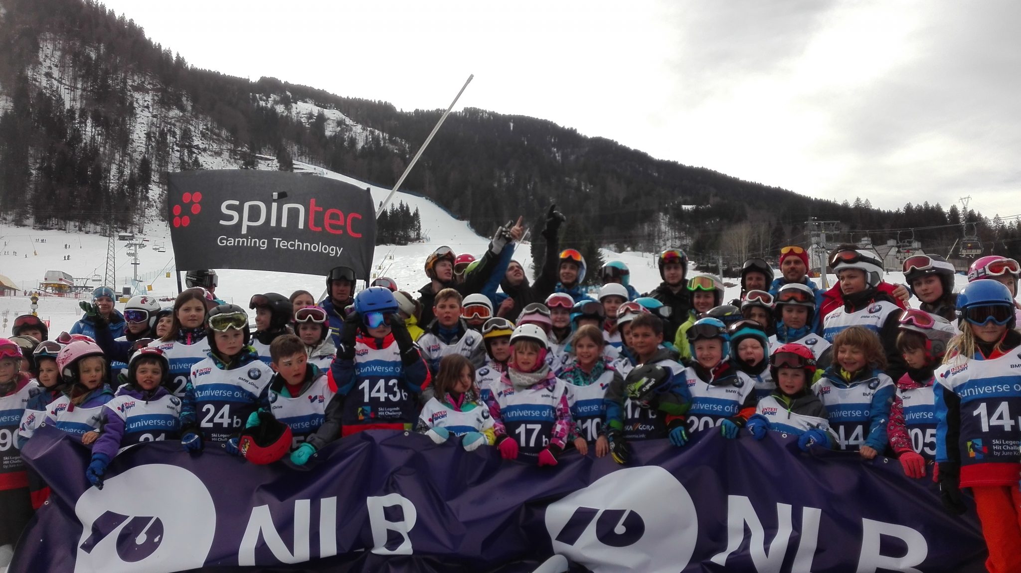 Velika skupina smučarjev, ki držijo transparente za Spintec in NLB
